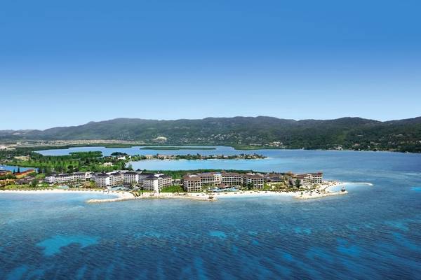 Luftaufnahme des Secrets St. James Hotel am Strand mit blauem Wasser und Bergen im Hintergrund