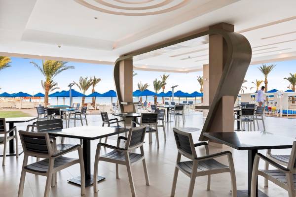Innenbereich des Pickalbatros Aqua Blu Resort in Hurghada mit Tischen, Stühlen und Blick auf den Strand.