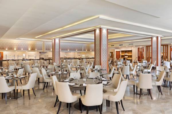 Innenbereich des Pickalbatros Aqua Blu Resort in Hurghada mit vielen eleganten Tischen und Stühlen.