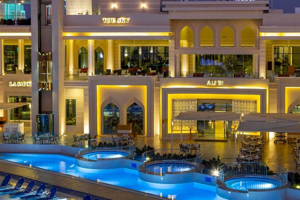 Pickalbatros Aqua Blu Resort in Hurghada bei Nacht mit beleuchtetem Swimmingpool und Außenbereich mit Tischen und Stühlen.