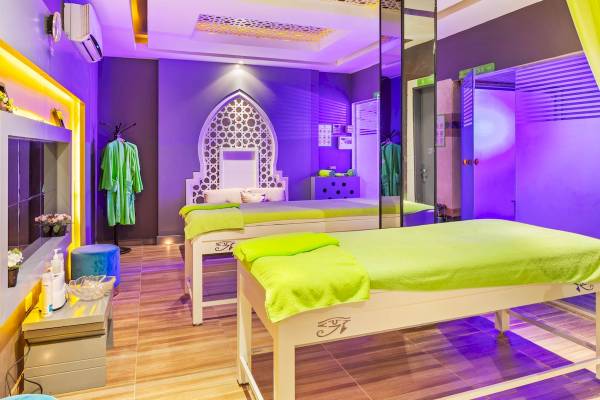 Wellnessbereich im Pickalbatros Aqua Blu Resort in Hurghada mit zwei Massagebetten, lila Beleuchtung und grünen Handtüchern.