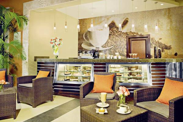Innenansicht des Cafés im Secrets St. James Hotel mit Möbeln und Dekoration.