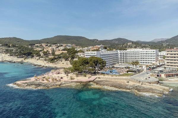 Luftaufnahme des ALUA Gran Camp de Mar Hotels am Strand mit grünem Wasser und Bergen im Hintergrund.