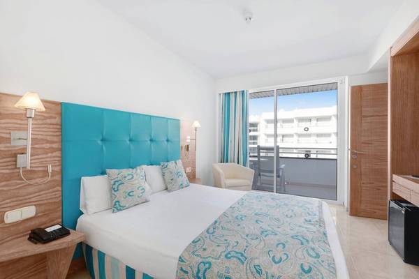 Hotelzimmer mit einem Bett, einem blauen Kopfteil, einem Balkon und einem Fenster.