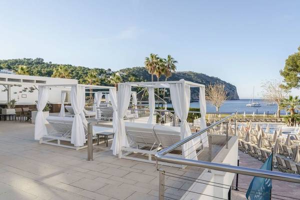 Außenbereich des ALUA Gran Camp de Mar Hotels mit weißen Sonnenliegen und Aussicht auf das Meer.