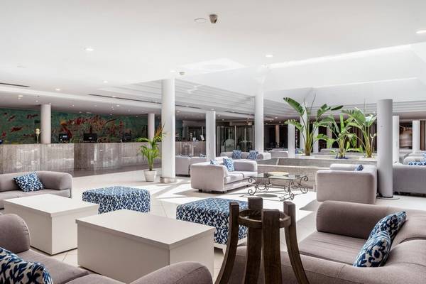 Modernes Hotellobby-Interieur des ALUA Gran Camp de Mar mit weißen Möbeln, bunten Kissen und Pflanzen.