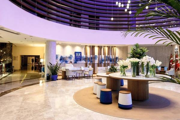 Lobby des TUI BLUE Side Hotels mit moderner Inneneinrichtung, Empfangstresen und Tisch mit Blumen.