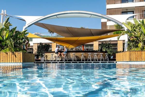 Poolbar im TUI BLUE Side Hotel mit zwei Personen, die unter einem gelben Sonnensegel sitzen
