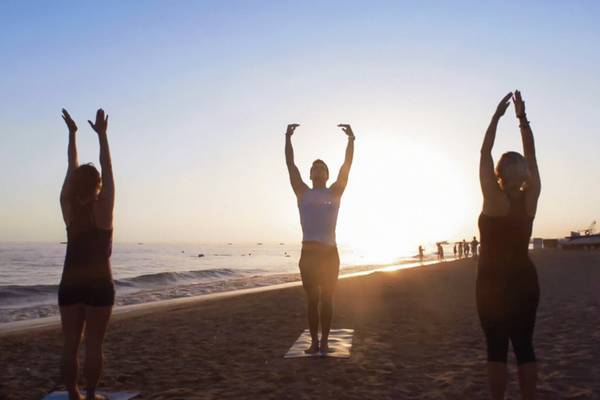 Drei Frauen praktizieren Yoga auf dem Strand vor dem TUI BLUE Side Hotel.