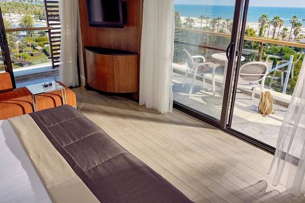 Zimmer im TUI BLUE Side Hotel mit Blick auf das Meer und eine Terrasse mit Möbeln.