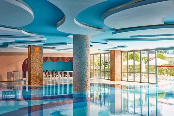 Innenpool des Magic Life Jacaranda Hotels mit blauen Decken und Säulen.