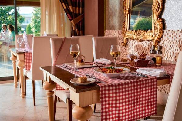 Gedeckter Esstisch im Speisesaal des Magic Life Jacaranda Hotels mit roten Tischdecken und goldenem Spiegel.