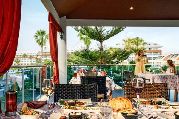 Essen auf der Terrasse im Magic Life Jacaranda Hotel mit Blick auf Palmen und Gebäude.