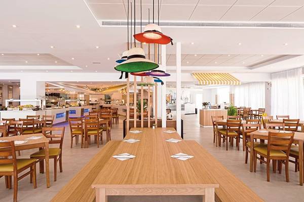 Innenansicht des Restaurants im Calimera Balansat Resort mit bunten Lampen, Holztischen und Stühlen.