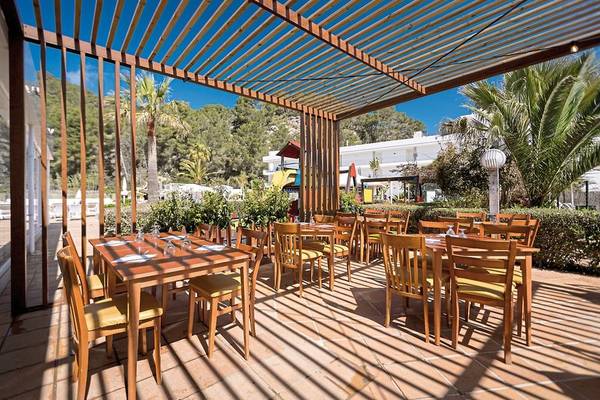 Restaurantterrasse des Calimera Balansat Resorts mit Holztischen und Stühlen unter einer Pergola.