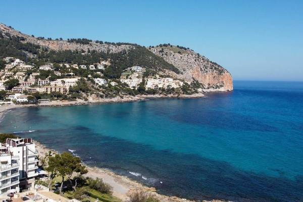 Aussicht auf das Canyamel Classic Hotel und die Bucht mit blauem Meer und grünem Hügel.