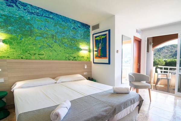 Hotelzimmer im Canyamel Classic mit Doppelbett, Kunstwerk an der Wand und Balkonzugang.