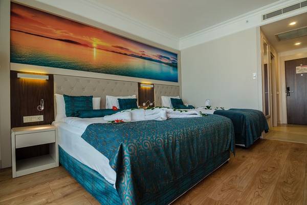 Zwei komfortable Hotelbetten mit blauen Bettdecken in einem luxuriösen Hotelzimmer mit Panoramameerblick