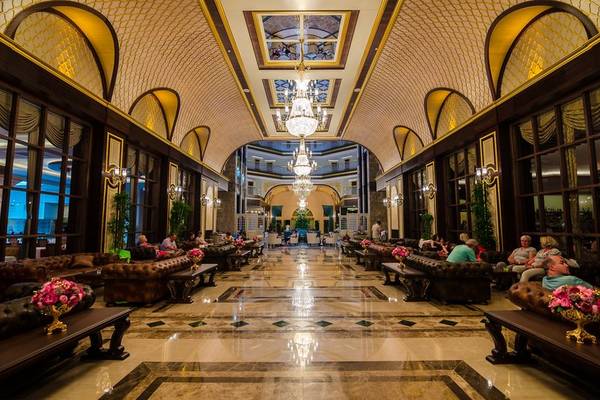 Lobby des Lumos Deluxe Resort Hotel mit braunen Ledersofas und kristallenen Kronleuchtern.