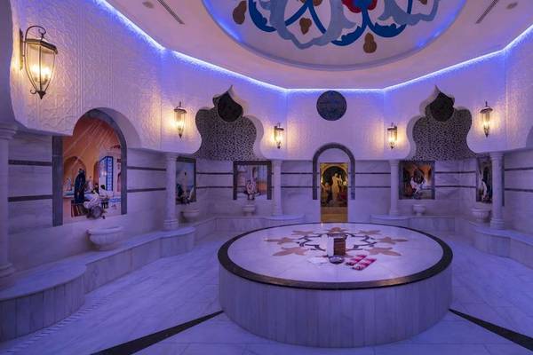 Innenansicht der Sauna im Granada Luxury Hotel Okurcalar mit weißen Marmorböden und Wänden, dekorativen Wandmalereien und blauen Lichtern.