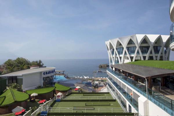Außenansicht des Granada Luxury Okurcalar Hotels mit Swimmingpool und Meer im Hintergrund.