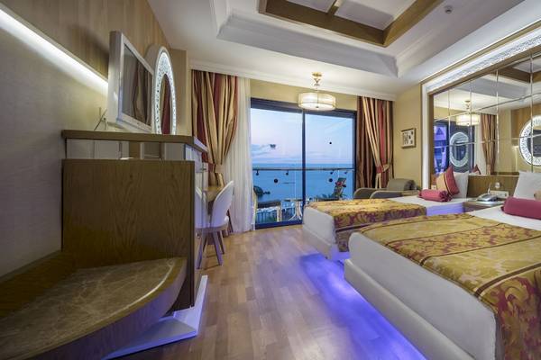 Innenansicht eines Hotelzimmers im Granada Luxury Okurcalar, mit zwei Betten, Meerblick und moderner Einrichtung.