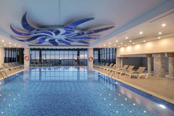 Innenpool des Hotel Granada Luxury Okurcalar mit vielen Liegen und einer modernen Deckengestaltung.