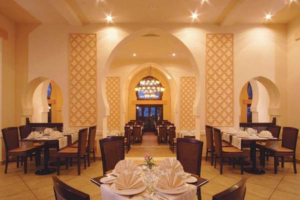 Innenansicht des Restaurants im Jaz Belvedere Resort mit gedeckten Tischen und Stühlen.