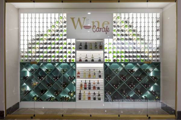 Weinkeller im Granada Luxury Okurcalar Hotel mit grün beleuchteten Flaschen und 'Wine Carafe' Schild.