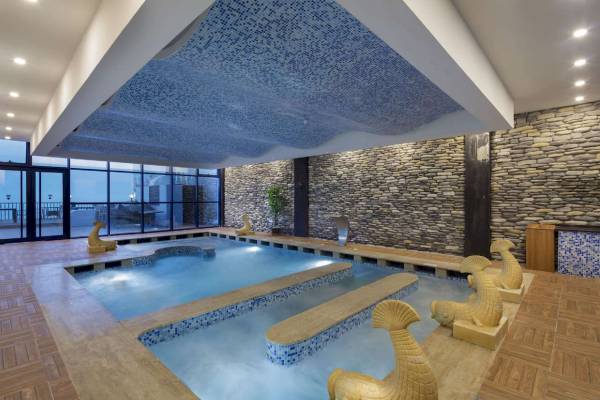 Innenpool im Granada Luxury Hotel Okurcalar mit blauer Decke und Steinwänden.