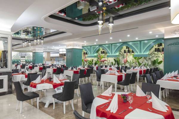 Innenansicht des Restaurants im Granada Luxury Okurcalar Hotel mit gefüllten Tischen und Flamingo-Wandmalerei.