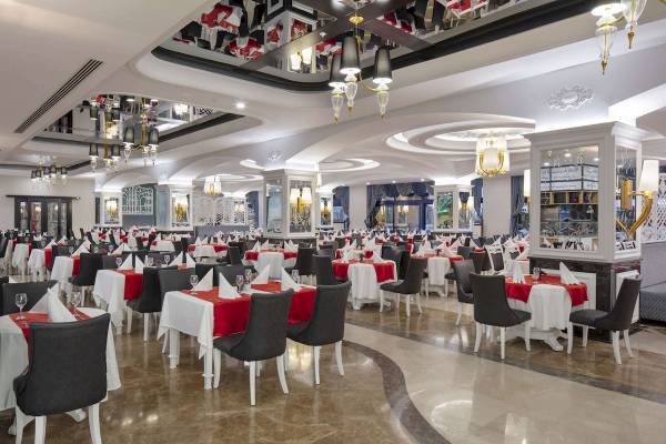 Innenansicht des Restaurants im Granada Luxury Okurcalar Hotel mit gedeckten Tischen und Stühlen.