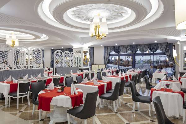 Innenansicht des Restaurants im Hotel Granada Luxury Okurcalar mit gedeckten Tischen und goldener Beleuchtung.