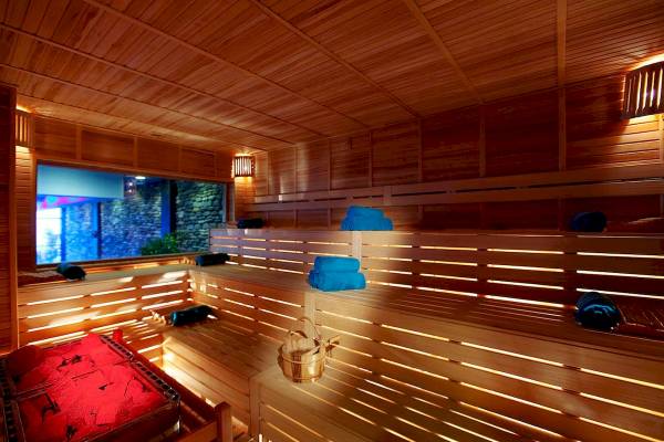 Innenansicht der Sauna im Hotel Granada Luxury Okurcalar mit Holzbänken, blauen Handtüchern und einem Eimer.