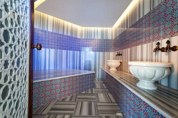 Ein Badezimmer des Granada Luxury Hotels mit blauen und roten geometrischen Wandfliesen und zwei Waschbecken.
