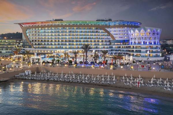 Abendansicht des Granada Luxury Okurcalar Hotels mit vielen Lichtern und Sonnenliegen am Strand