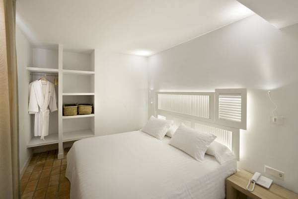 Schlafzimmer im Paraiso de los Pinos Hotel mit weißem Bett, Kissen und Kleiderschrank.