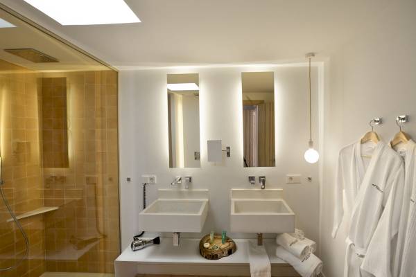 Badezimmer im Paraiso de los Pinos Hotel mit zwei Waschbecken, einer Dusche und weißen Handtüchern.
