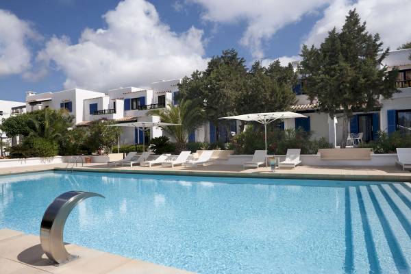 Pool-Bereich des Paraiso de los Pinos Hotels mit weißen Liegestühlen und Schirmen.