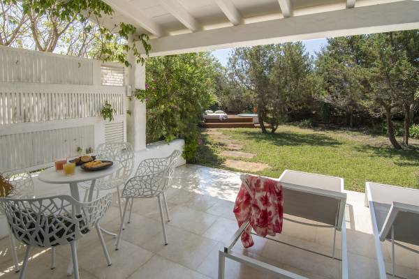 Terrasse des Paraiso de los Pinos Hotels mit Tisch, Stühlen und Blick auf einen Garten.