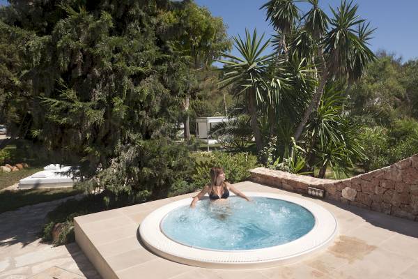 Frau im Whirlpool im Paraiso de los Pinos Hotel, umgeben von Bäumen und Pflanzen.