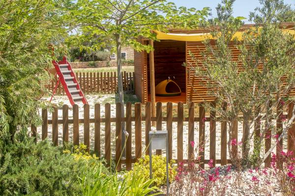 Außenbereich des Paraiso de los Pinos Hotels mit einem Hundehaus und einer roten Rutsche.