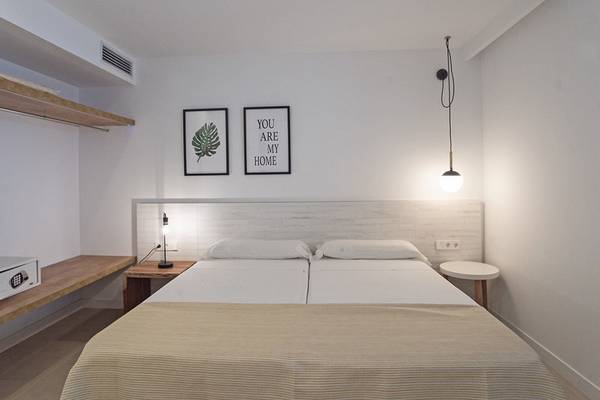 Doppelzimmer im Apartamentos Es Pujols mit zwei Betten, weißen Wänden und modernen Dekorationen.