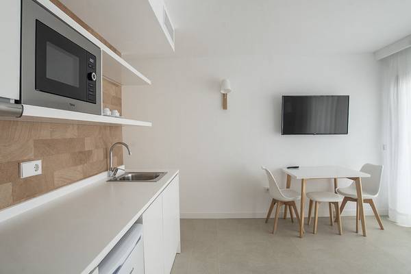 Küche im Apartamentos Es Pujols Hotel mit Tisch und Fernseher