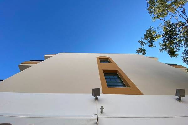 Außenansicht des Rosales Formentera Hotels mit weißer Fassade und braunen Fensterrahmen.