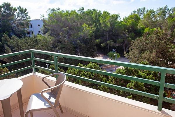 Balkon des Rosales Formentera Hotels mit Tisch, Stühlen und Blick auf eine bewaldete Landschaft