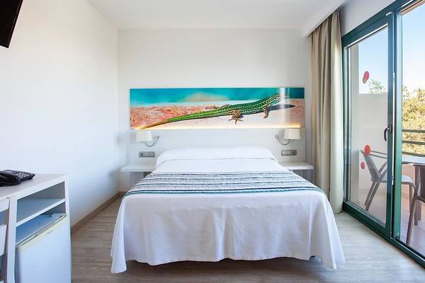Rosales Formentera Hotelzimmer mit Bett, Fernseher und Balkonzugang.