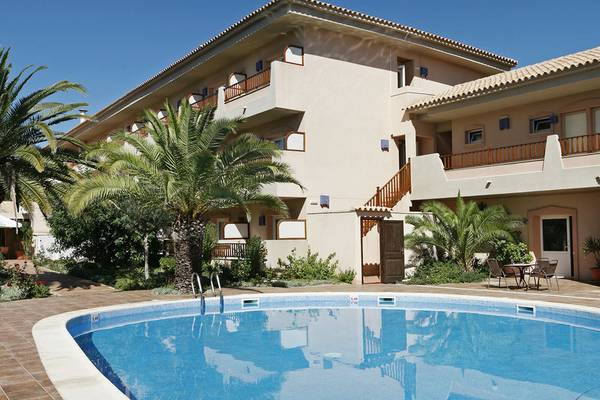 Außenbereich des Voramar Formentera Hotels mit Swimmingpool, Palmen und Terrassen.