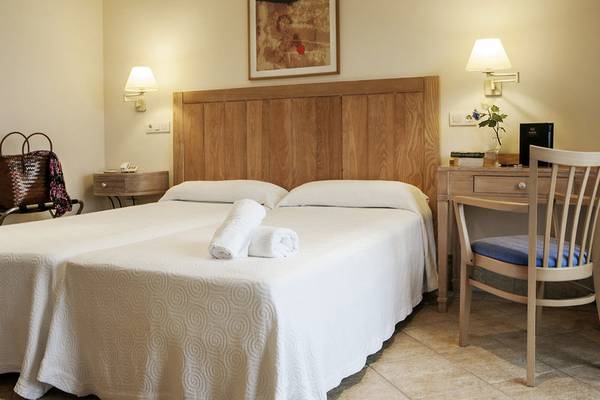 Doppelbett-Zimmer im Hotel Voramar Formentera mit weißem Bettzeug und Holzkopfteil.