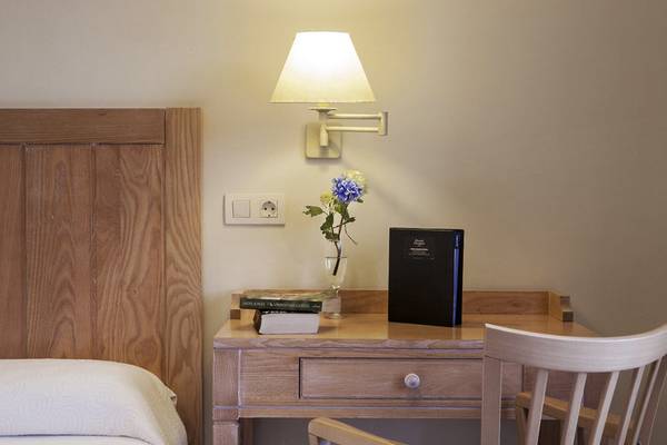 Blick auf den Schreibtischbereich im Voramar Formentera Hotelzimmer mit Lampe, Blumen, Büchern und Nachttisch